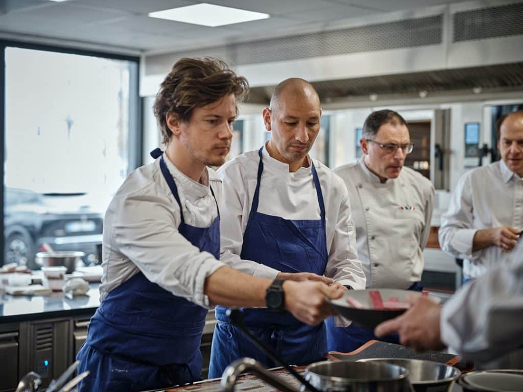 students presenting their dishes to chef on kitchen